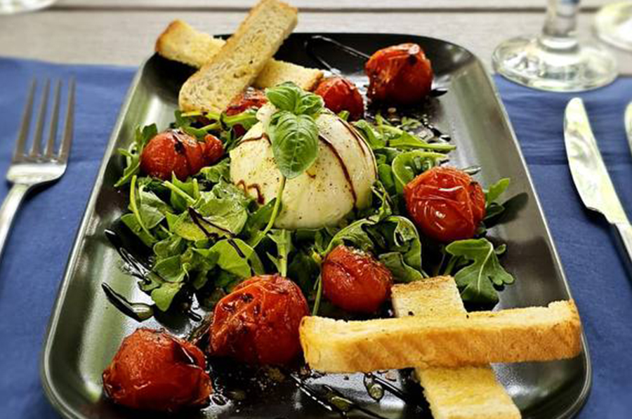 Burrata mit gebackenen Kirschtomaten, bestreut mit Basilikum und Olivenöl